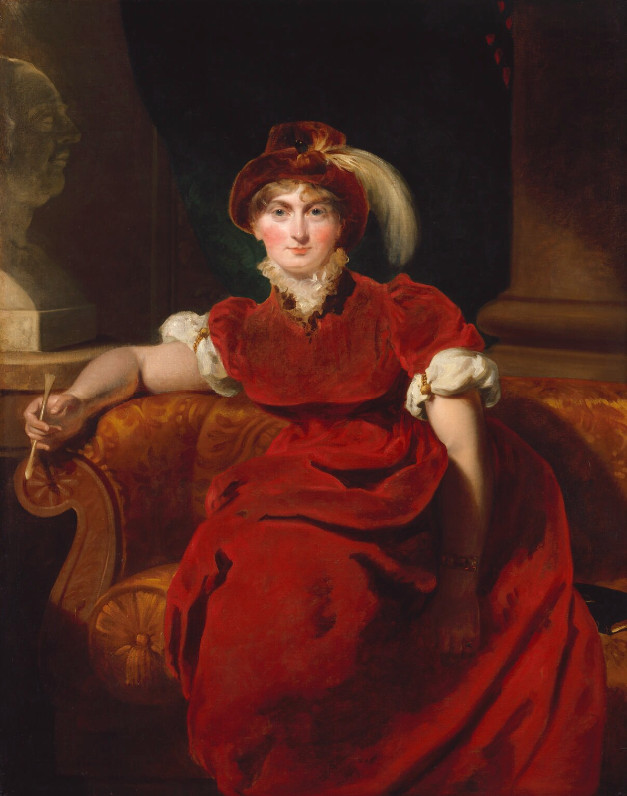 Caroline in a red velvet dress and hat, celebrating sculpture